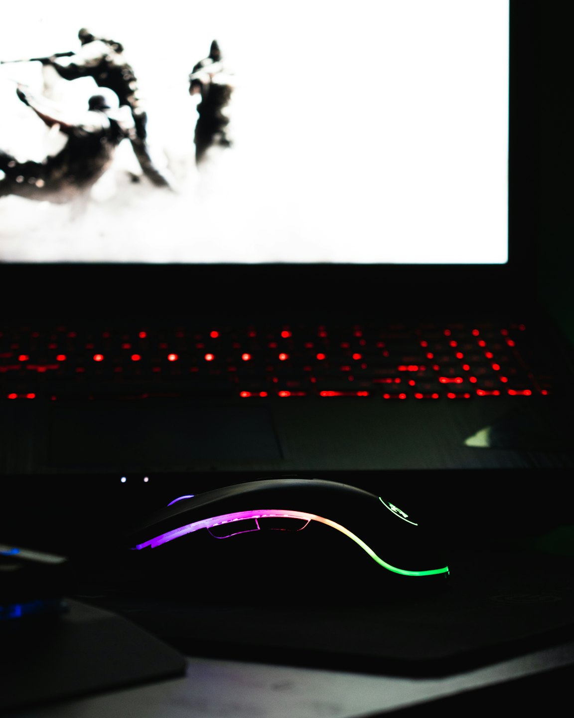 Ratón para juegos con luces RGB de colores sobre un escritorio.