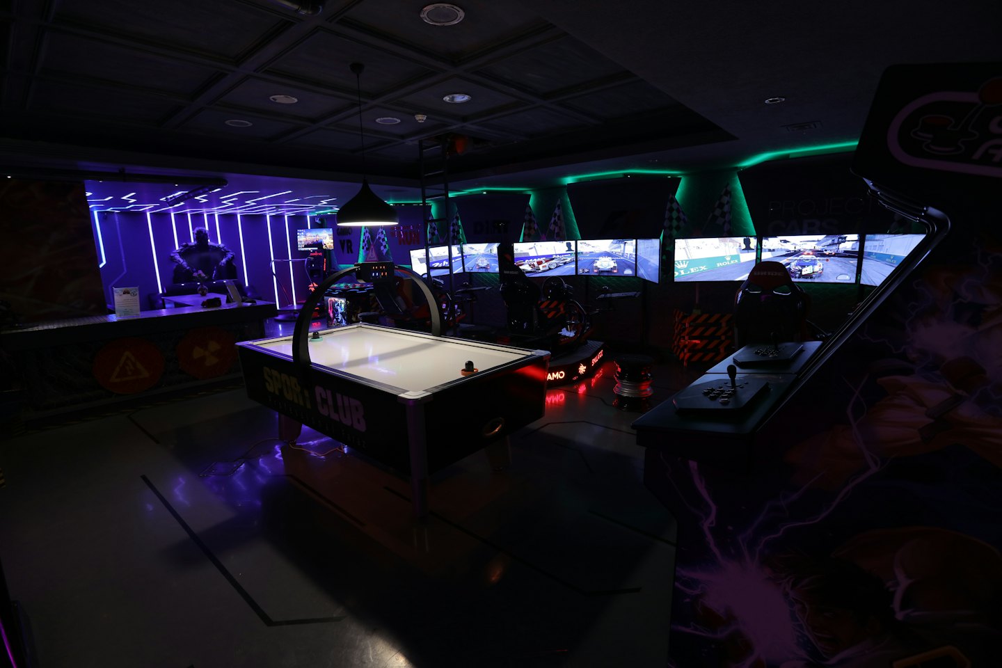 Sala de juegos recreativos con air hockey y simuladores de carreras.