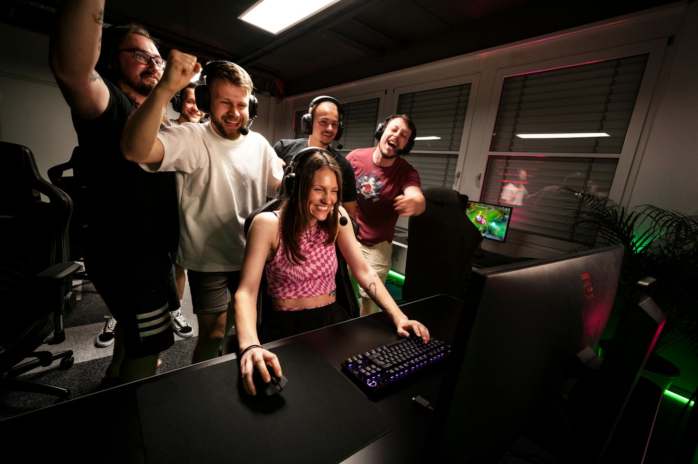 Mujer jugando videojuegos mientras hombres celebran a su alrededor.
