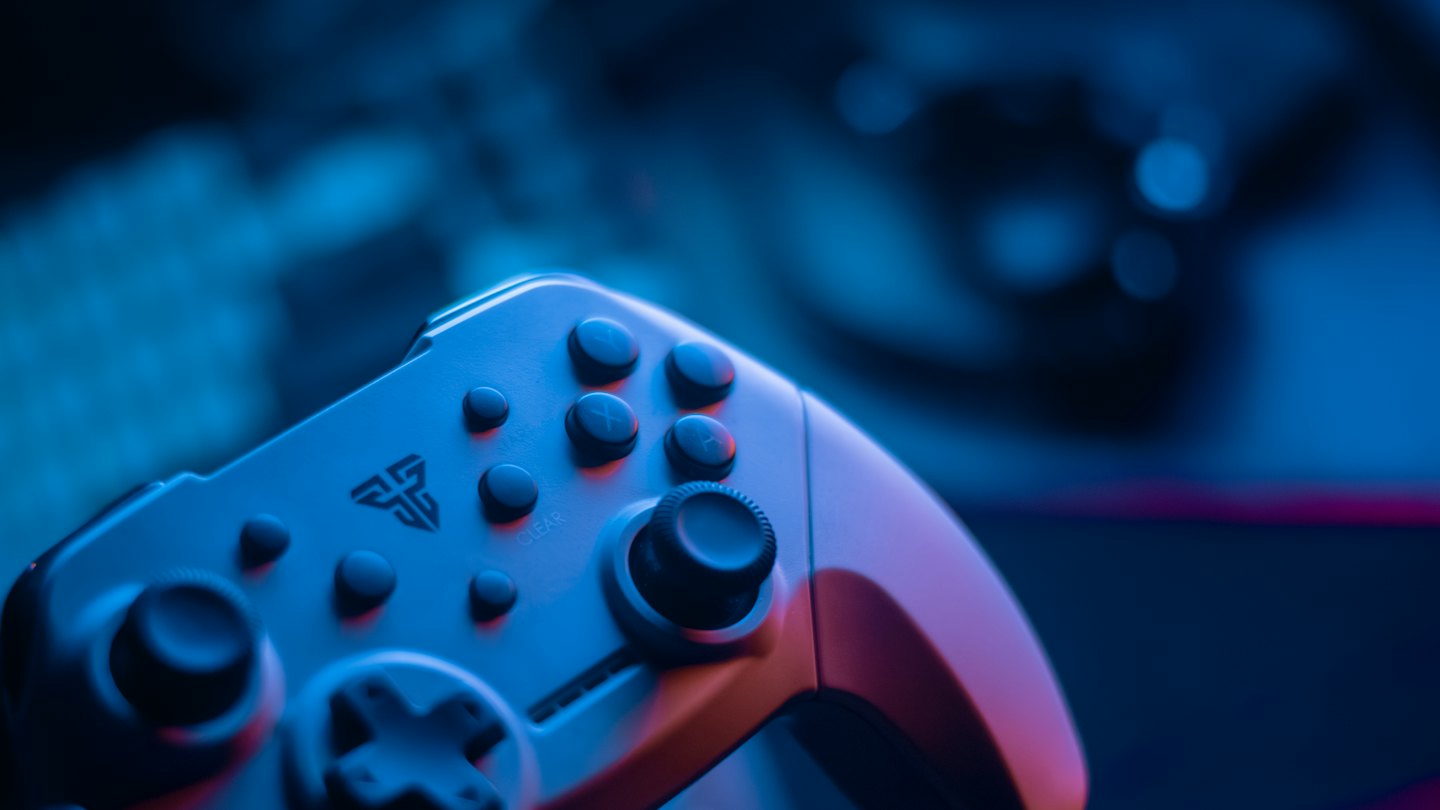 Mando de videojuegos blanco moderno iluminado por luces de neón.